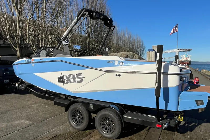 Slide: The Image of 2024 Axis T220 boat on trailer, dockside with clear blue sky background. - 18