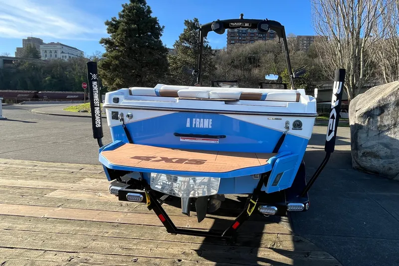 Slide: The Image of 2024 Axis T220 boat with blue and white design, parked outdoors on a sunny day. - 19