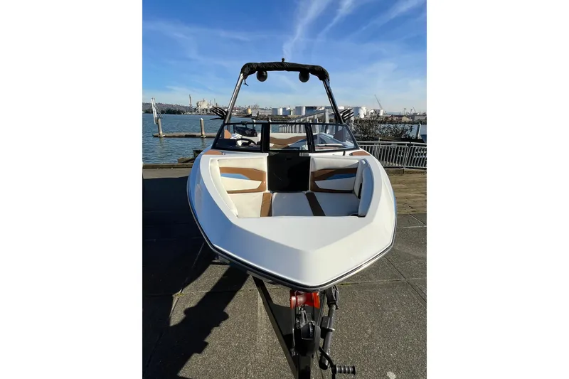 Slide: The Image of 2024 Axis T220 boat docked by waterfront, showcasing sleek design and spacious seating. - 4