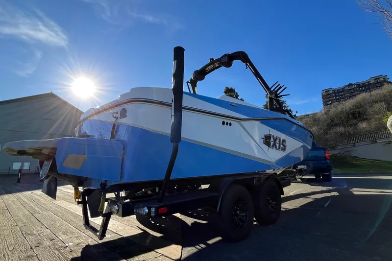 Slide: The Image of 2024 Axis T220 boat on trailer, sunlit, with blue and white design. - 8