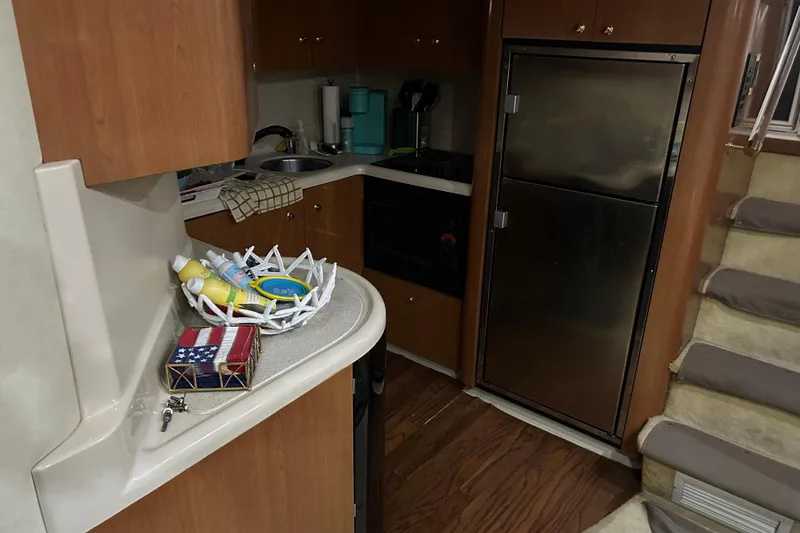 Slide: The Image of 1998 Cruisers Yachts 4270 Express interior kitchen with wooden cabinets and stainless steel fridge. - 14