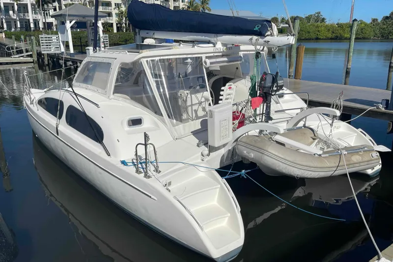 Slide: The Image of 1998 Maine Cat Catamaran docked with inflatable dinghy, clear skies, and calm waters. - 17