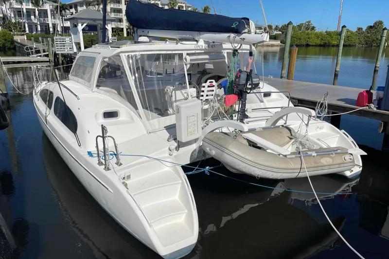 Slide: The Image of 1998 Maine Cat Catamaran docked with inflatable dinghy, clear skies, and calm waters. - 18