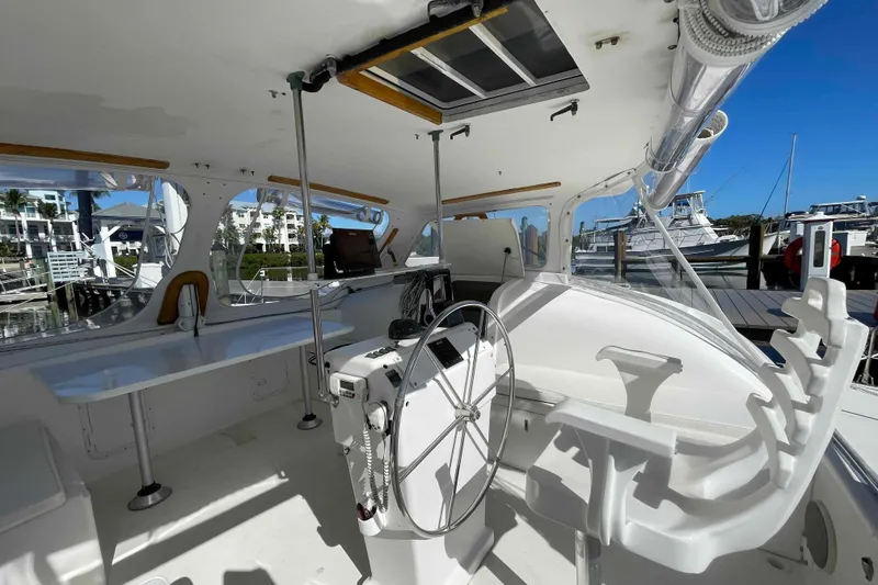 Slide: The Image of 1998 Maine Cat Catamaran cockpit with steering wheel, docked at marina. - 30