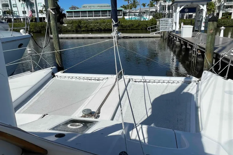 Slide: The Image of 1998 Maine Cat Catamaran docked at marina, featuring spacious deck and clear canopy. - 64