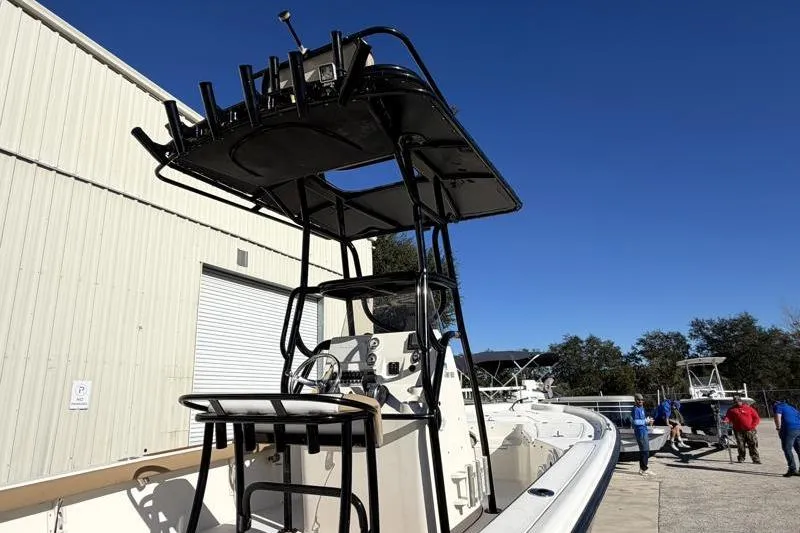 Slide: The Image of 2016 Key West 230 Bay Reef boat with T-top, parked near a warehouse. - 18