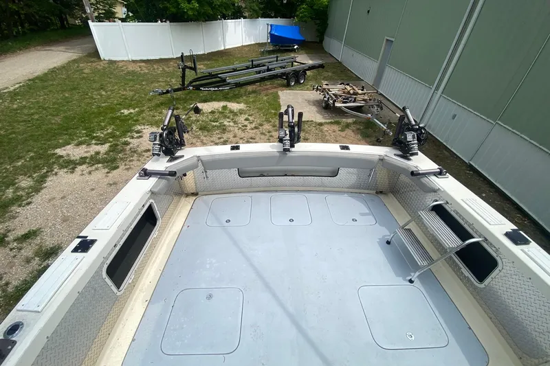 Slide: The Image of 1977 Bertram 28 Flybridge boat deck with fishing rod holders and trailers in the background. - 10