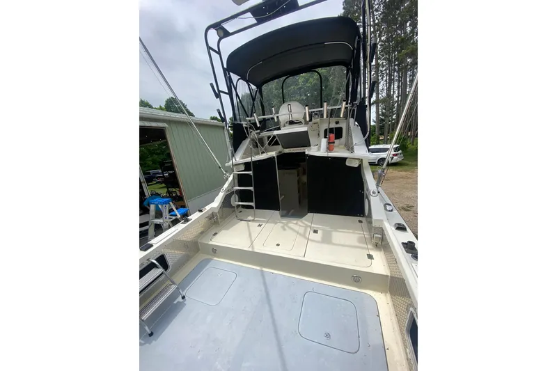 Slide: The Image of 1977 Bertram 28 Flybridge boat with spacious deck and flybridge, docked outdoors. - 11