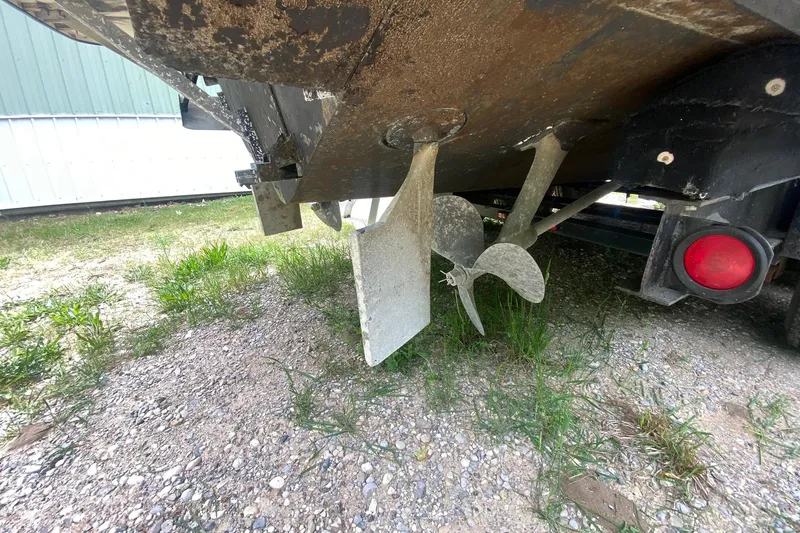 Slide: The Image of 1977 Bertram 28 Flybridge boat propeller and rudder on gravel surface. - 15