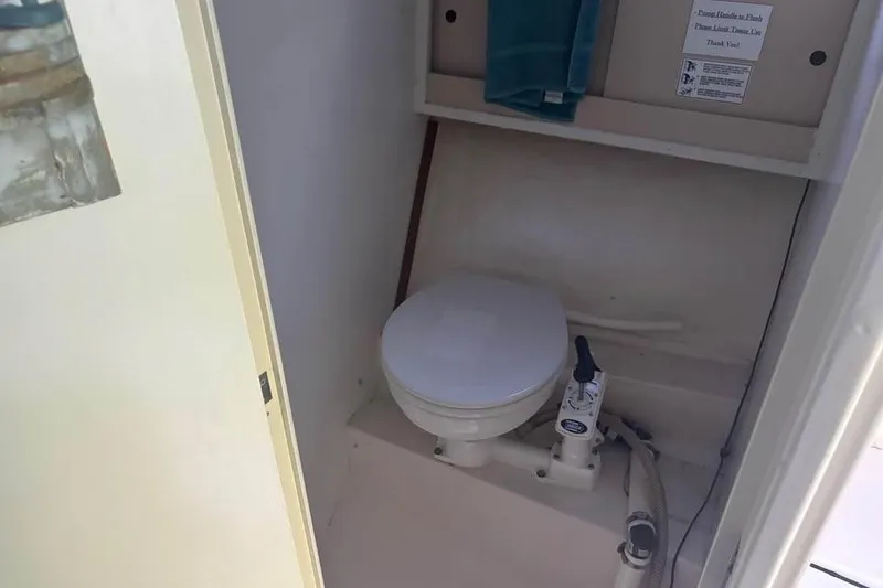 Slide: The Image of 1977 Bertram 28 Flybridge boat bathroom with marine toilet and storage shelf. - 22