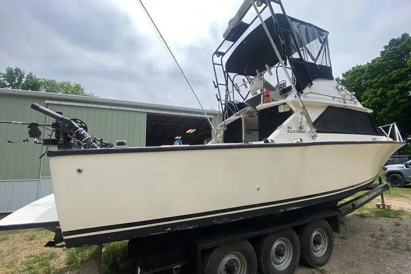 Slide: The Image of 1977 Bertram 28 Flybridge boat on trailer, parked near a green building. - 5
