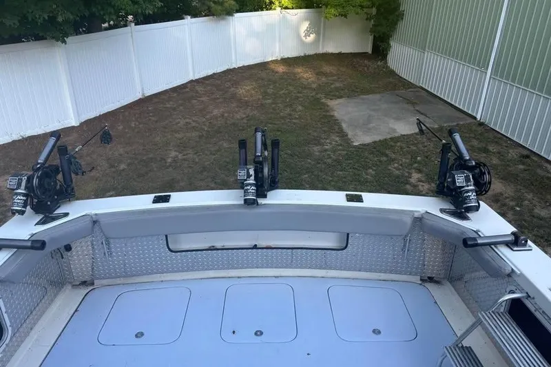 Slide: The Image of 1977 Bertram 28 Flybridge boat deck with fishing rod holders, in a fenced yard. - 8