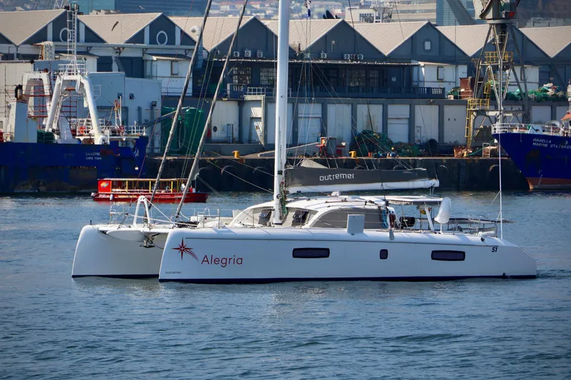 The Image of 2017 Outremer 51 catamaran "Alegria" docked in an industrial harbor setting. - 0