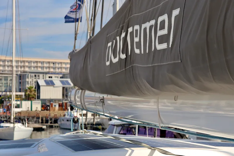Slide: The Image of 2017 Outremer 51 catamaran docked at a marina, showcasing its sail and branding. - 112
