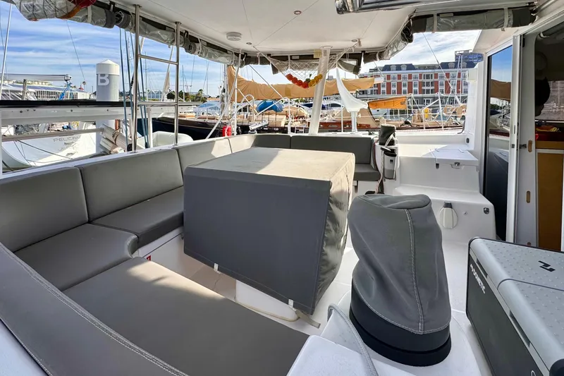 Slide: The Image of 2017 Outremer 51 catamaran cockpit with gray seating and marina view. - 12