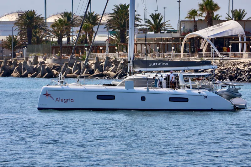 Slide: The Image of 2017 Outremer 51 catamaran "Alegria" docked near palm trees and waterfront buildings. - 134