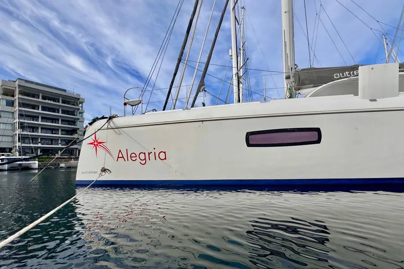 Slide: The Image of 2017 Outremer 51 catamaran "Alegria" docked in marina, modern building in background. - 5