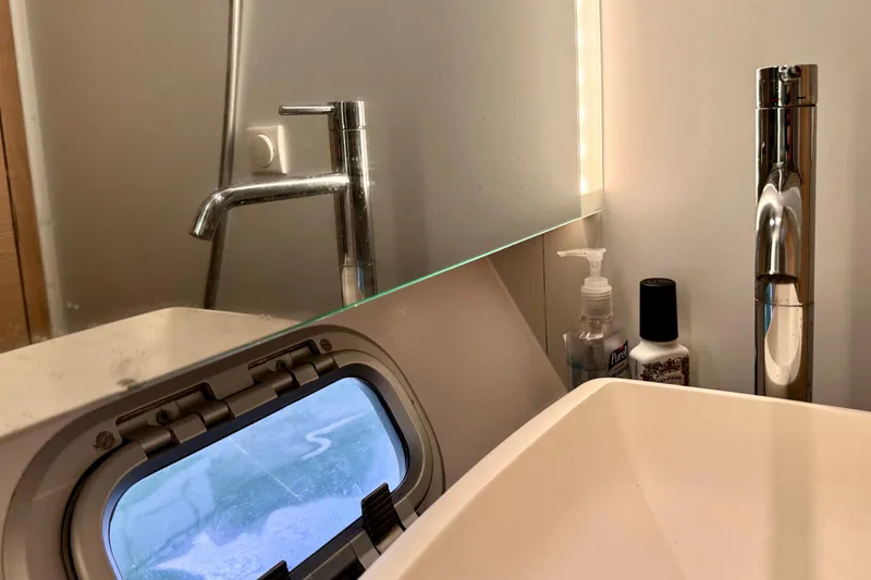 Slide: The Image of Bathroom sink area on 2017 Outremer 51 yacht with modern fixtures and porthole. - 53
