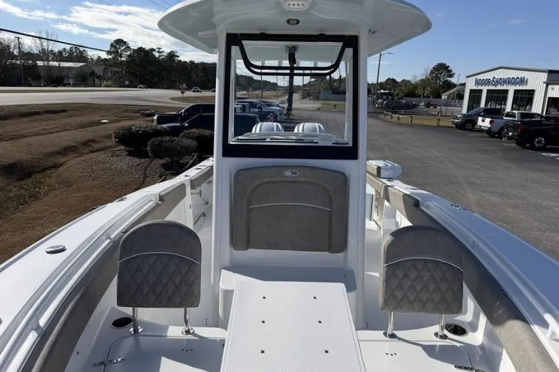 Slide: The Image of 2026 Sea Hunt Ultra 275 SE boat interior with seating and console, parked outdoors. - 14