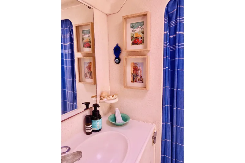 Slide: The Image of Bathroom in 1992 Privilege 482 with framed art, blue curtain, and toiletries. - 19