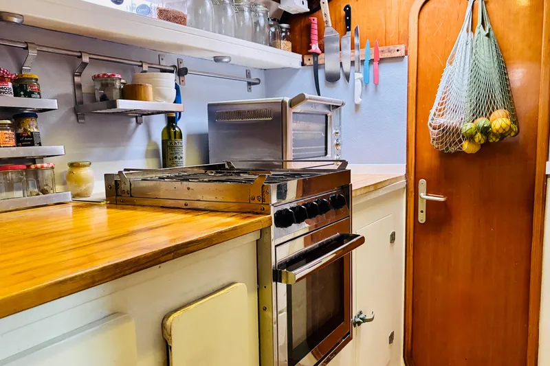 Slide: The Image of Compact kitchen in a 1992 Privilege 482 yacht with wooden countertops and hanging fruit net. - 27