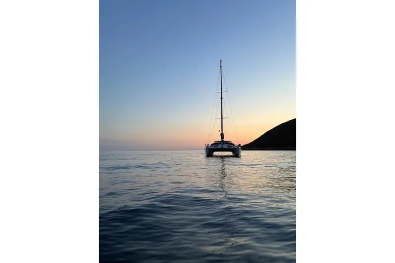 Slide: The Image of Sailing catamaran Privilege 482 at sunset, 1992 model, on calm sea. - 3