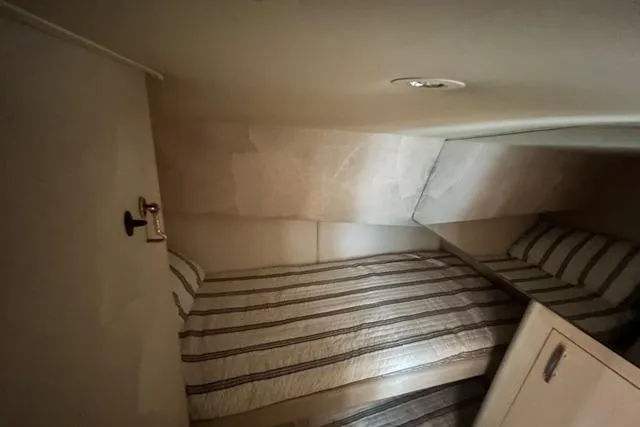 Slide: The Image of 1995 Ocean 53 Super Sport yacht cabin with striped bedding and compact design. - 8