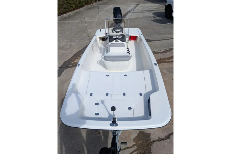 Slide: The Image of 2026 Mako Pro Skiff 17 CC boat, white interior, center console, parked on concrete. - 3