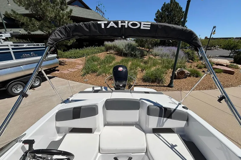 Slide: The Image of 2026 Tahoe T18 boat with canopy, parked near landscaped garden. - 11