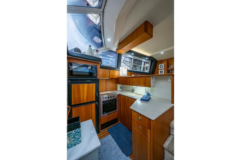 Slide: The Image of Interior of 2000 Silverton 442 Cockpit Motor Yacht kitchen with wood cabinetry and modern appliances. - 16