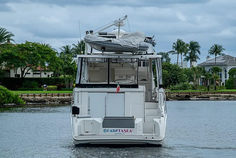 Slide: The Image of 2000 Silverton 442 Cockpit Motor Yacht on water, surrounded by lush greenery and palm trees. - 4