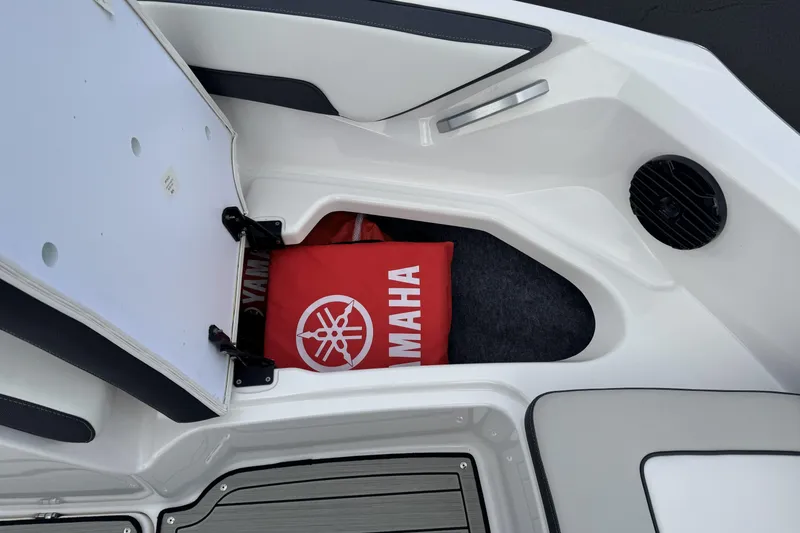 Slide: The Image of 2024 Yamaha Boats 195S storage compartment with Yamaha-branded cushion. - 10