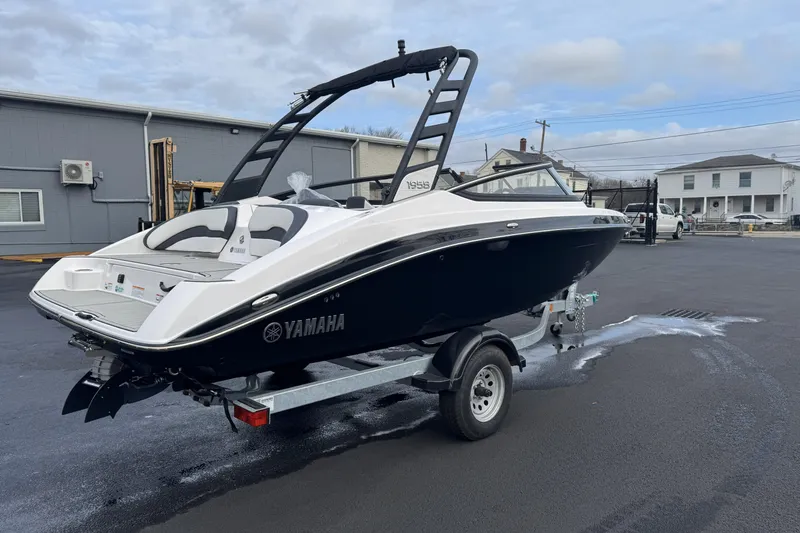 Slide: The Image of 2024 Yamaha Boats 195S on trailer, sleek black and white design, parked outdoors. - 2