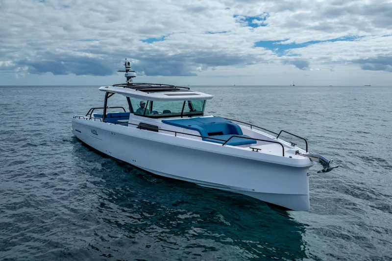 Slide: The Image of 2025 Axopar 45 Cross Top boat cruising on open water under cloudy skies. - 10