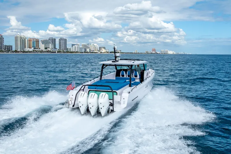 Slide: The Image of 2025 Axopar 45 Cross Top cruising near city skyline on open water. - 15