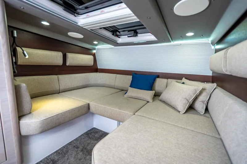 Slide: The Image of Luxurious interior of 2025 Axopar 45 Cross Top with beige seating and blue accent pillow. - 24