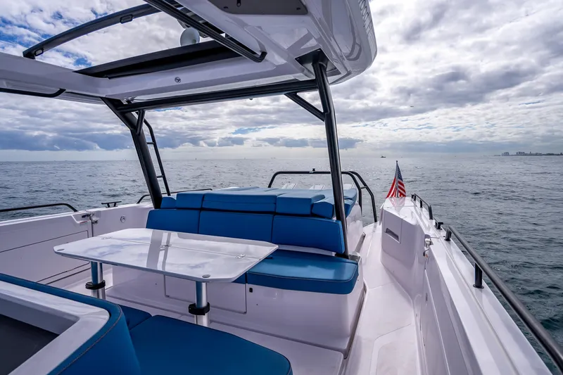 Slide: The Image of 2025 Axopar 45 Cross Top boat with blue seating, ocean view, and American flag. - 32