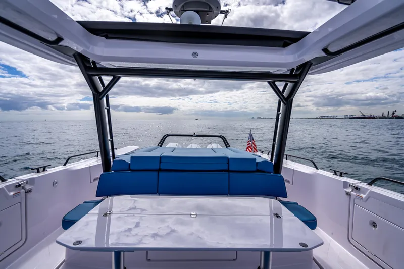 Slide: The Image of 2025 Axopar 45 Cross Top boat with blue seating, open sea view, and American flag. - 33