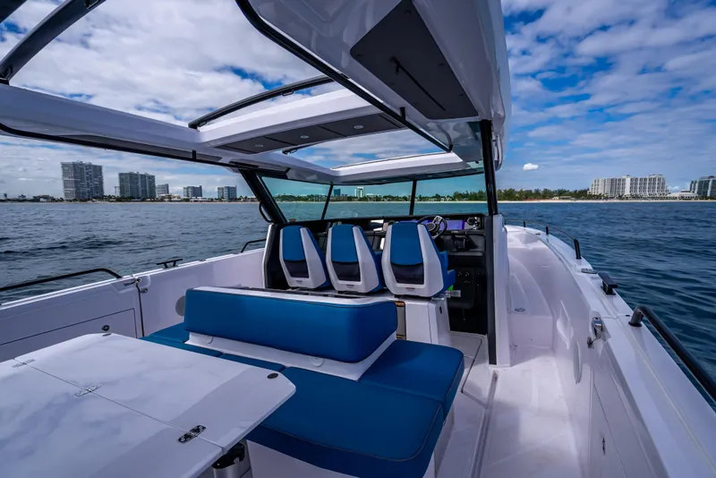 Slide: The Image of 2025 Axopar 45 Cross Top boat interior with blue seating, ocean view, and city skyline. - 38