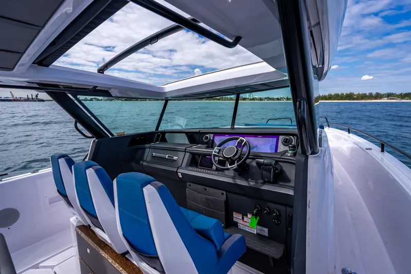 Slide: The Image of 2025 Axopar 45 Cross Top boat interior with blue seats and modern dashboard on open water. - 39