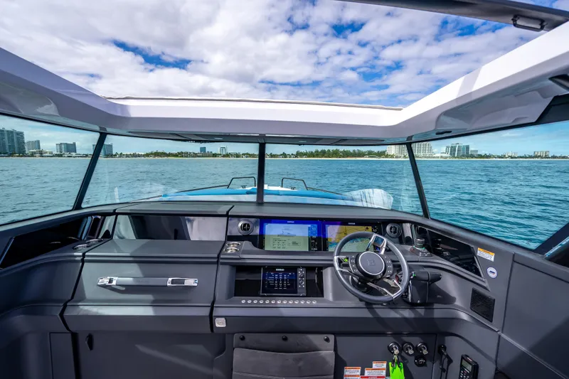 Slide: The Image of 2025 Axopar 45 Cross Top boat cockpit with modern navigation system, steering wheel, and ocean view. - 47