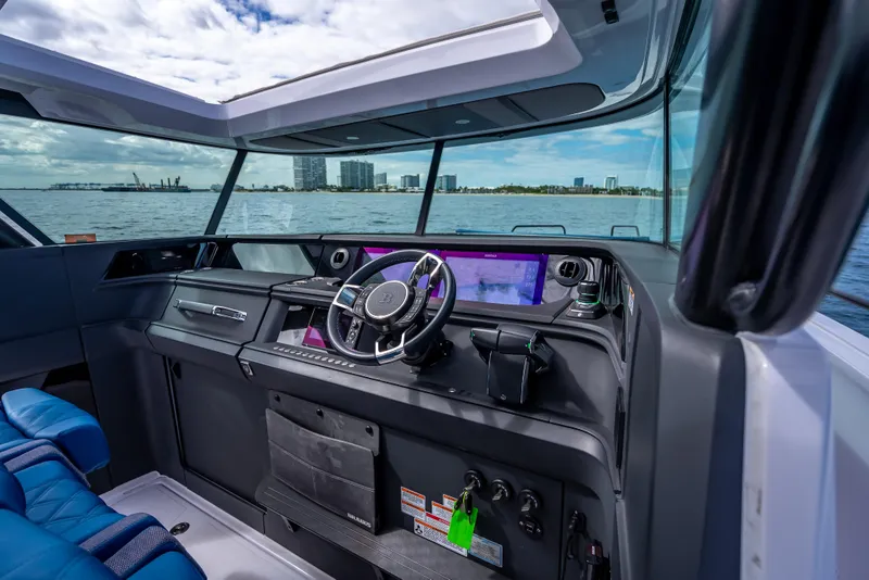 Slide: The Image of Interior view of 2025 Axopar 45 Cross Top boat cockpit with modern controls and ocean backdrop. - 48