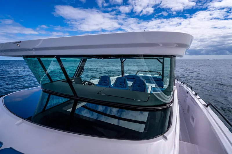 Slide: The Image of 2025 Axopar 45 Cross Top boat on open water under blue sky. - 52