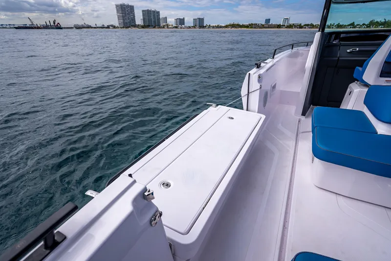 Slide: The Image of 2025 Axopar 45 Cross Top boat with blue seating, docked near a city skyline. - 55