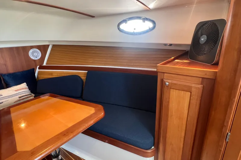 Slide: The Image of 2005 Back Cove 29 interior with wooden table, blue seating, and fan. - 46