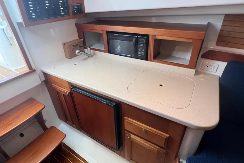 Slide: The Image of 2005 Back Cove 29 boat interior kitchen with sink, microwave, and wooden cabinetry. - 50