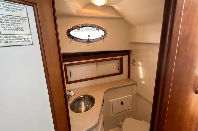 Slide: The Image of 2005 Back Cove 29 boat bathroom with sink, porthole, and storage cabinet. - 53