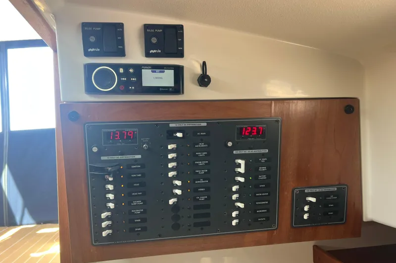 Slide: The Image of Electrical panel of a 2005 Back Cove 29 boat, featuring bilge pump controls and a Fusion stereo system. - 56