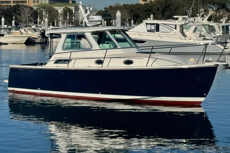 Slide: The Image of 2005 Back Cove 29 boat docked in a marina, reflecting on calm water. - 7