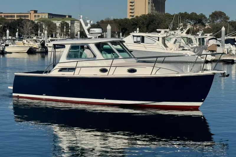 Slide: The Image of 2005 Back Cove 29 boat docked in a marina, reflecting on calm water. - 8